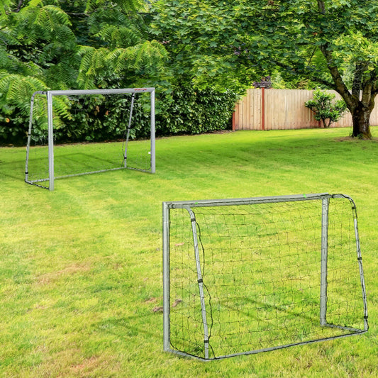 Two soccer goals on a grassy field with trees and a wooden fence in the background.
