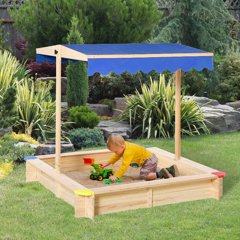 Child playing in a wooden sandbox with a canopy in a garden setting