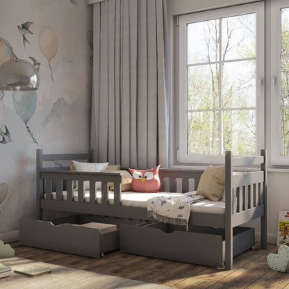 Children's bedroom with a gray bed featuring storage drawers, pink owl pillow, and wooden floor.