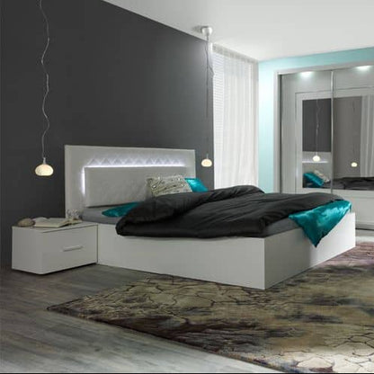 Modern bedroom with a white bed, nightstand, and decorative rug.